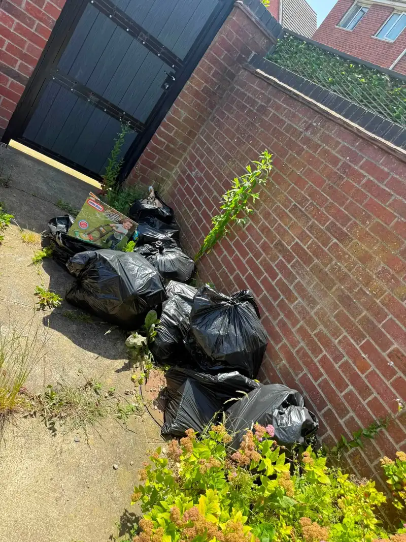A side alley piled with bin bags and household rubbish before clearance