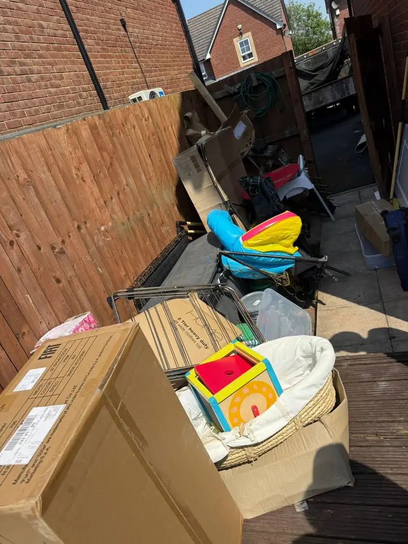 A side passage stacked with boxes, furniture and garden tools before clearance